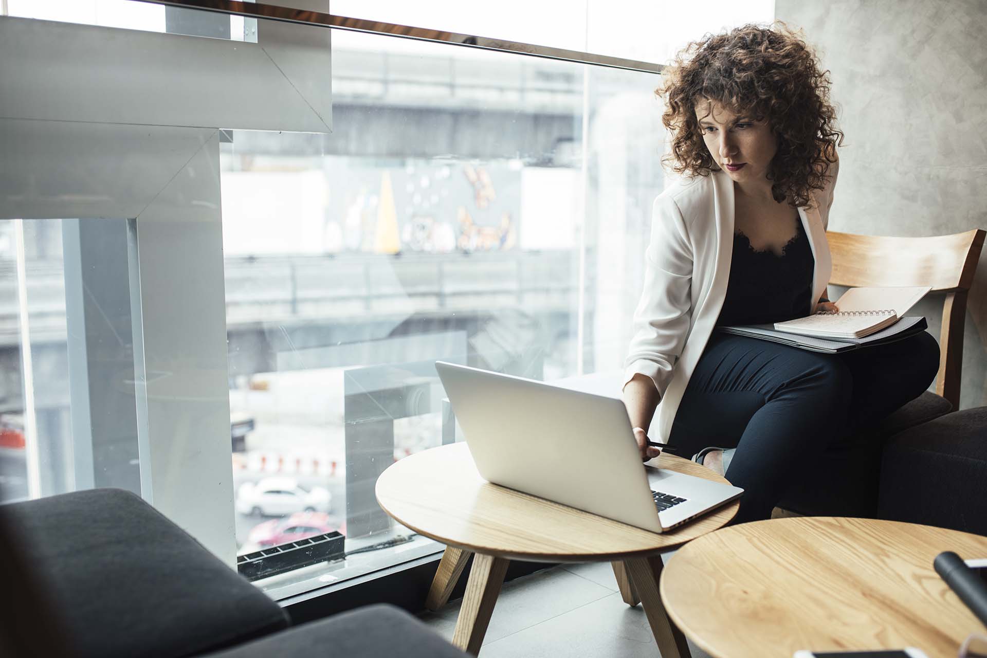 Pretty Caucasian businesswoman sitting at coffee shop and working on her laptop.