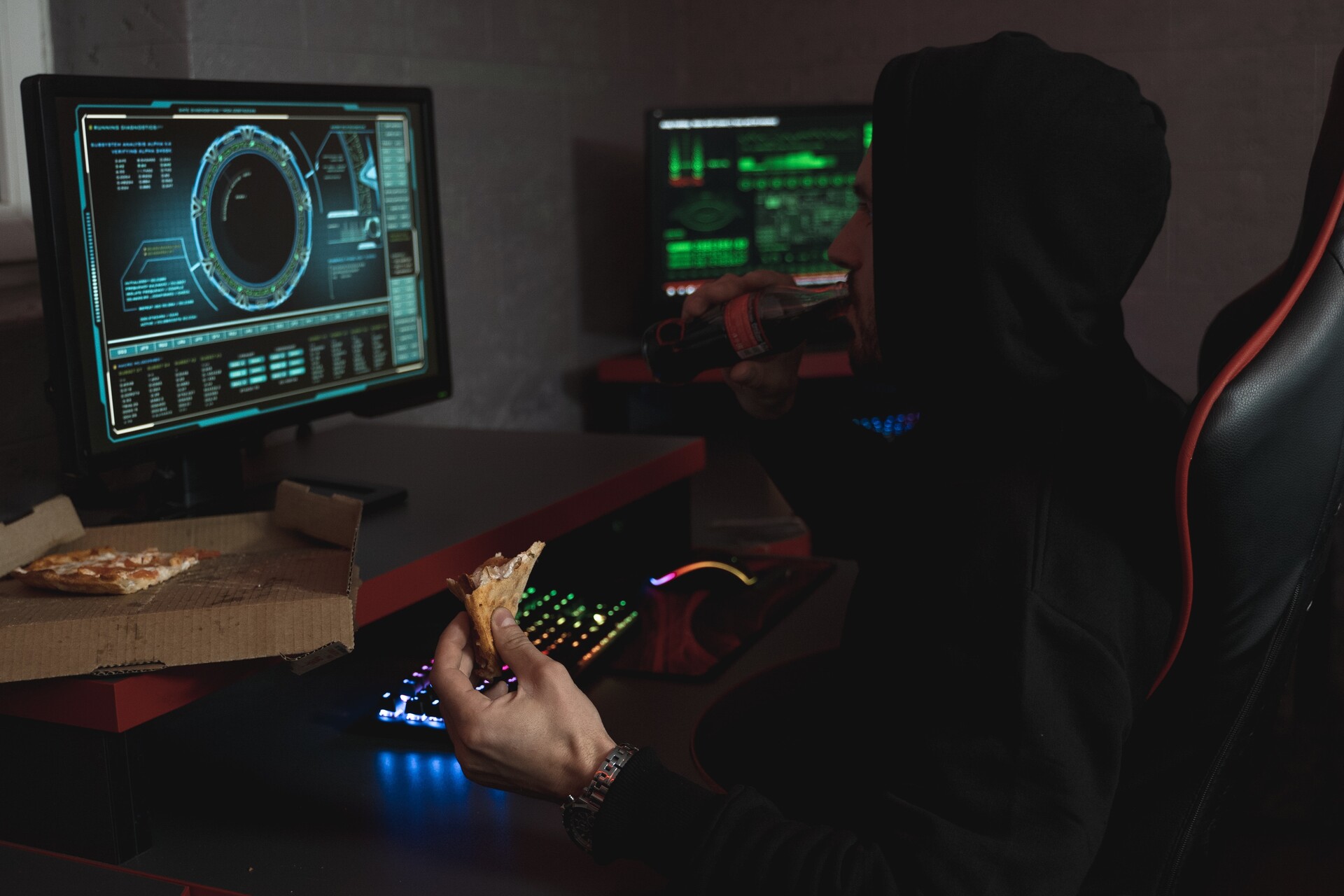 A man in a hoodie eating a pizza