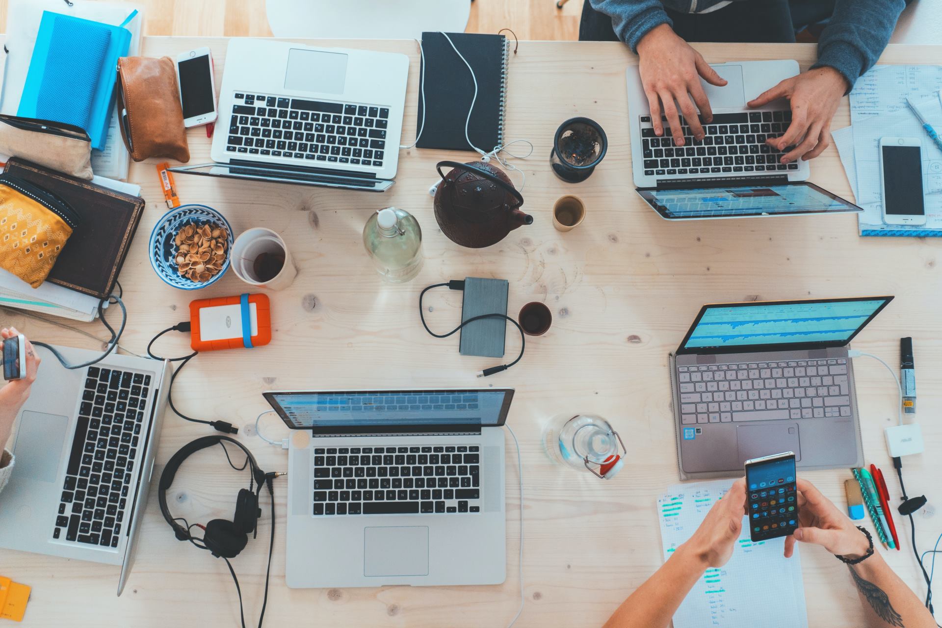 Aerial view of the desk with five laptops and people working on them