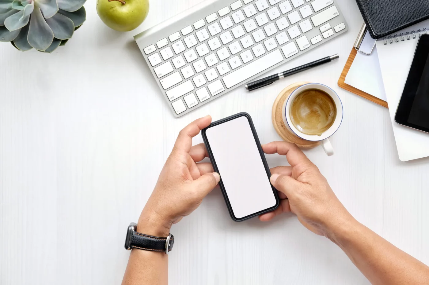 A person holding a phone and a keyboard next to them