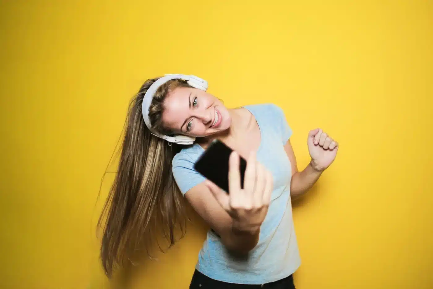 A woman looking at a phone and wearing headphones