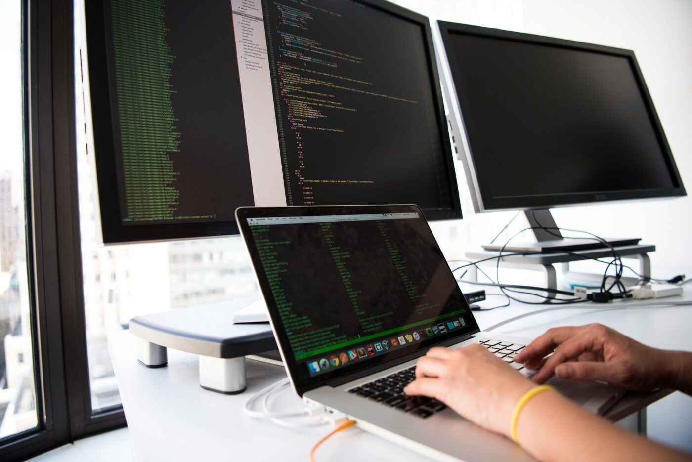 A developer working on a laptop computer with several monitors