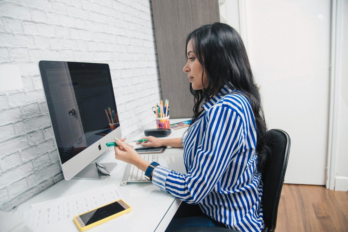 A woman working on an Apple desktop computer