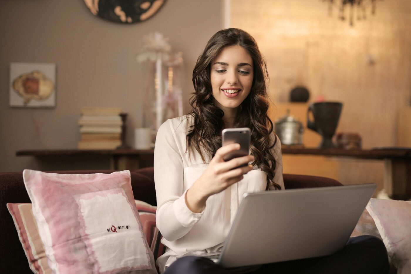 A woman using both a smartphone and a laptop